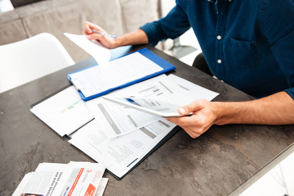 Cropped picture of young man's hands holding documents. Focus on hands with documents.